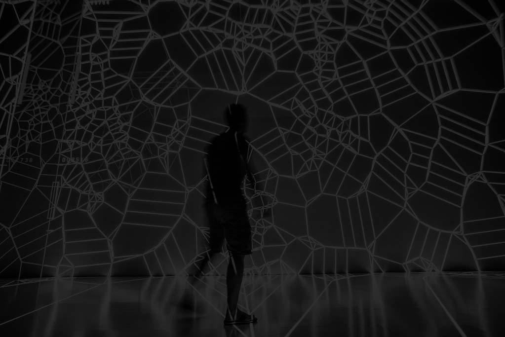 silhouette of a body walking through a tangle of bright white strings that are connected to look like DNA or some other sort of network